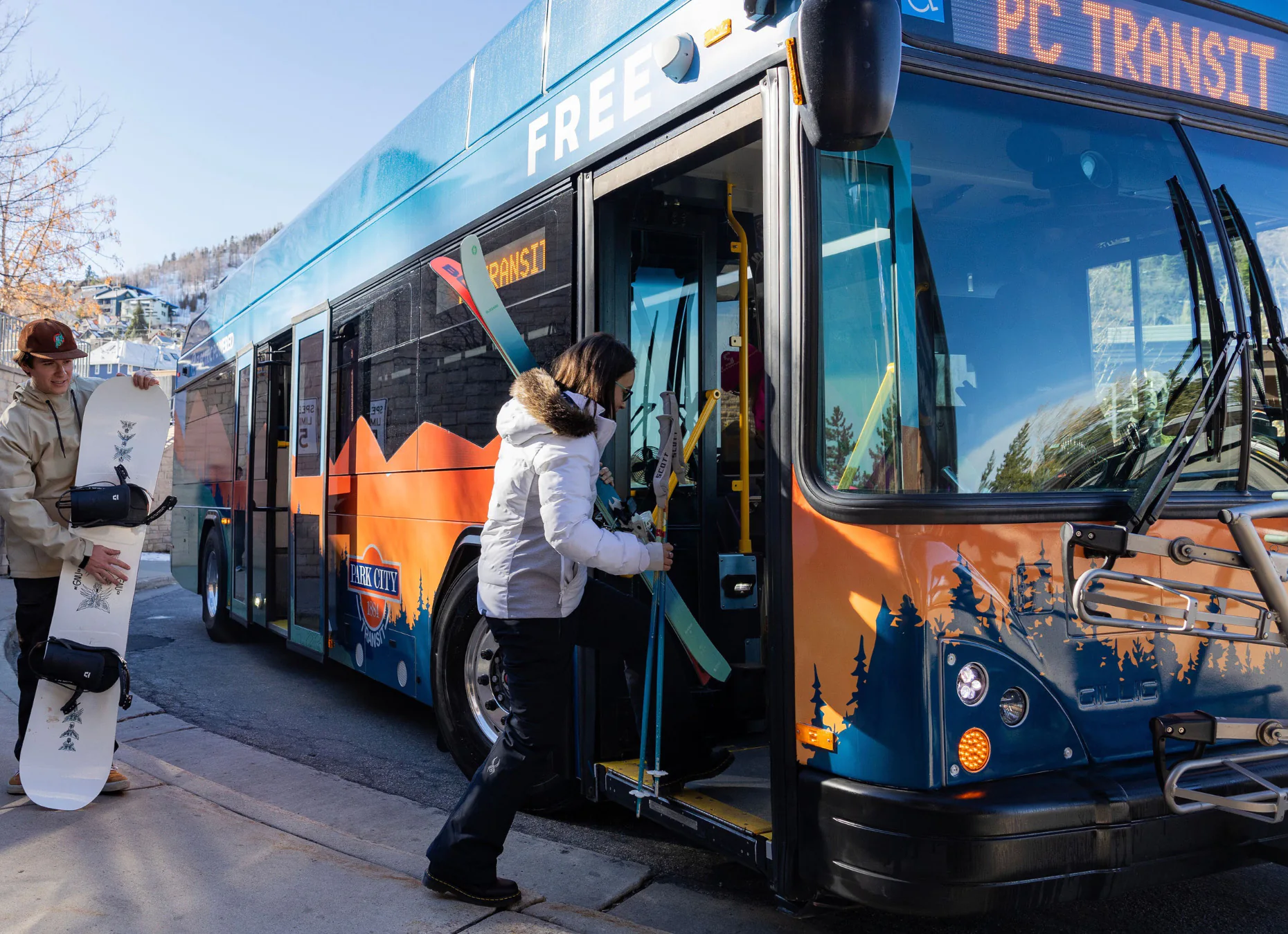 A skier and snowboarder board a Park City Transit bus.